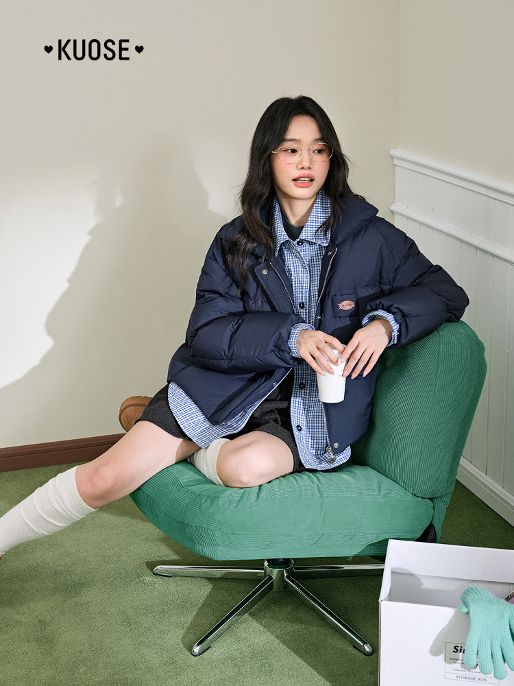 Model wearing a navy puffer jacket with a layered shirt outfit