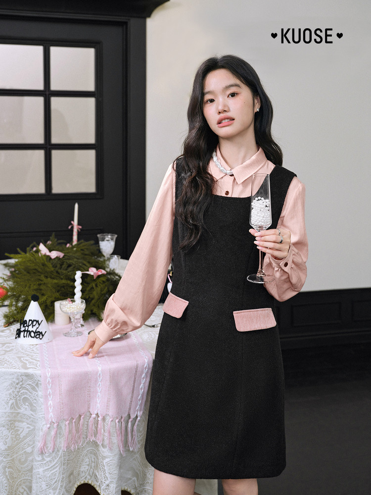 Model wearing a black pinafore dress over a pink blouse