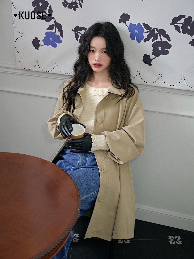 Model wearing a beige long coat over a light knit top and jeans