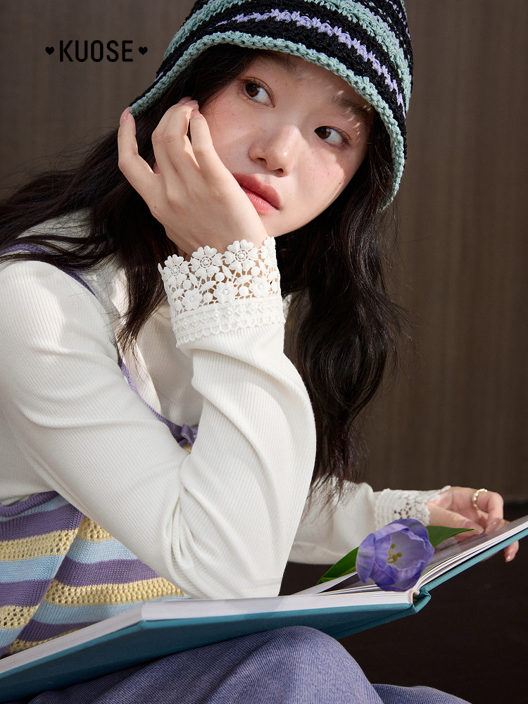 Model wearing a striped knit bucket hat and layered knit top with lace cuffs