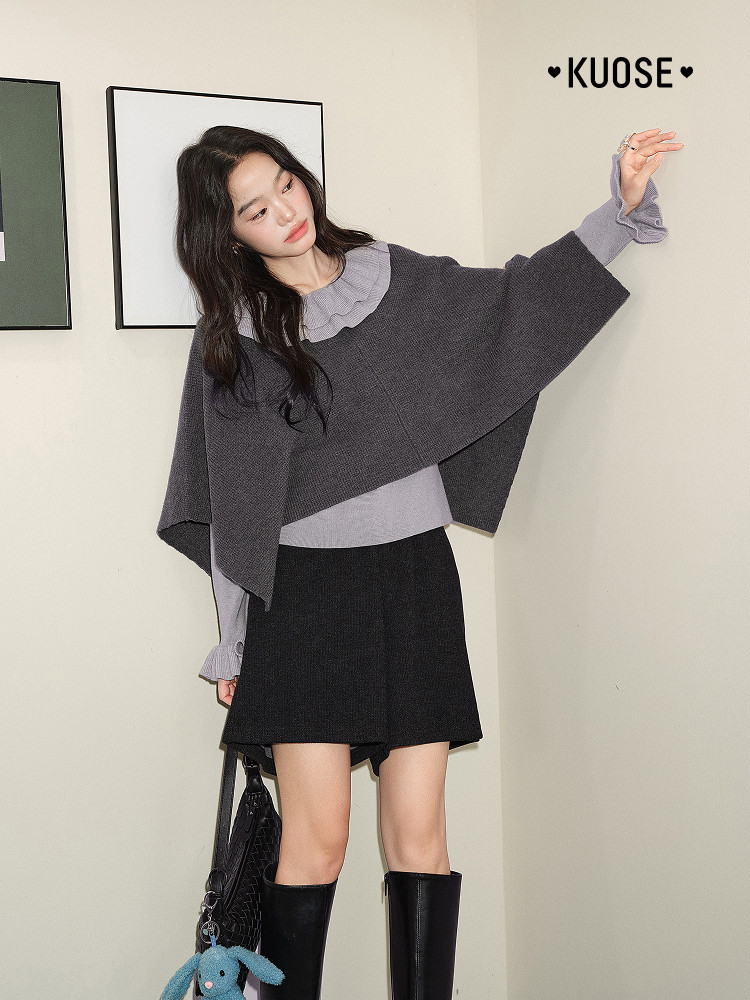 Model wearing a gray knit poncho-style top with black skirt and boots