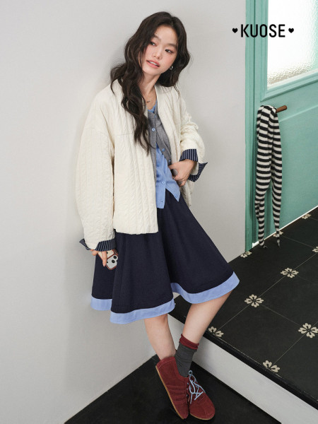 Female model wearing a cream jacket with a layered dress outfit and red shoes