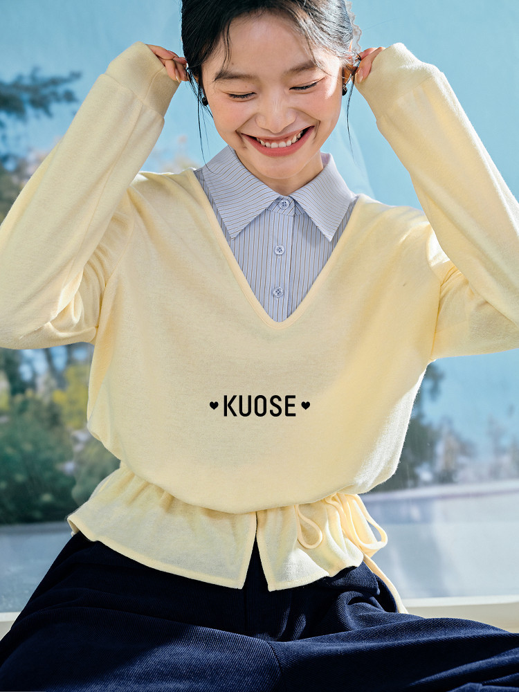 Model wearing a pale yellow V-neck sweater layered over a striped shirt