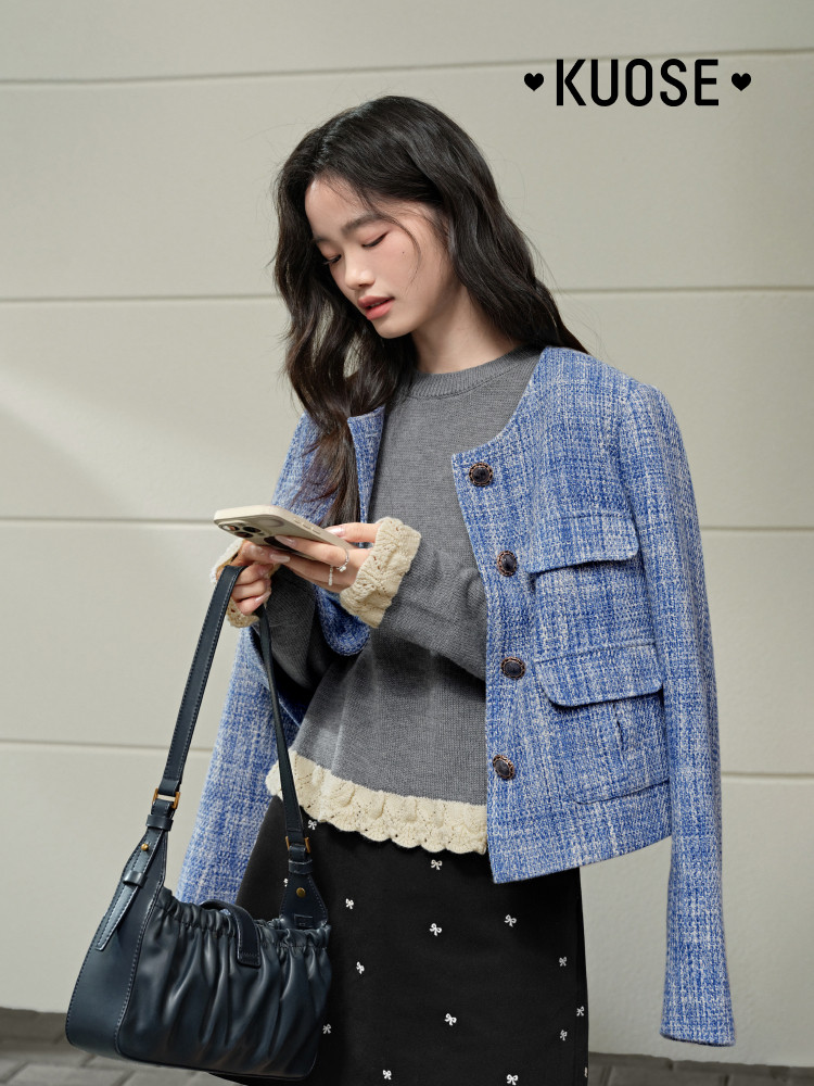 Model wearing a blue tweed jacket over a gray top with a black handbag