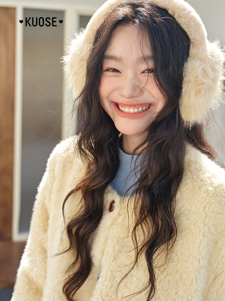 Model wearing a cream fuzzy sweater and fluffy earmuffs