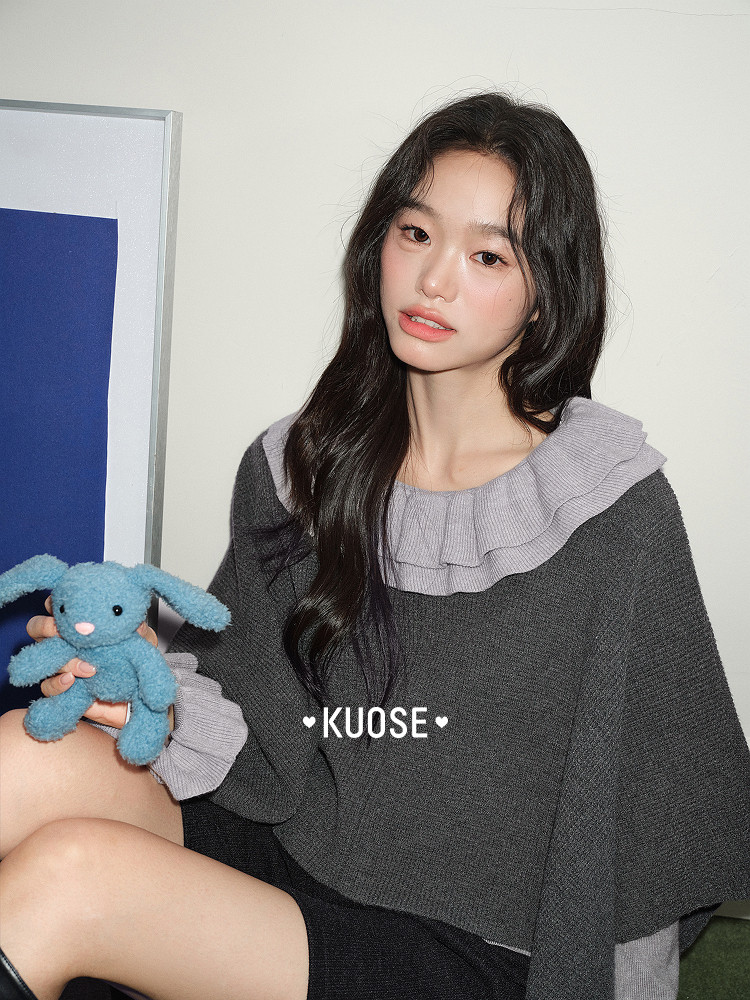 Female model wearing a dark gray ruffled knit top with long sleeves