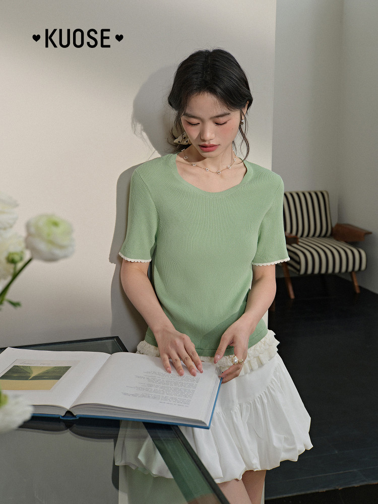 Model wearing a light green ribbed short-sleeve top with a white skirt