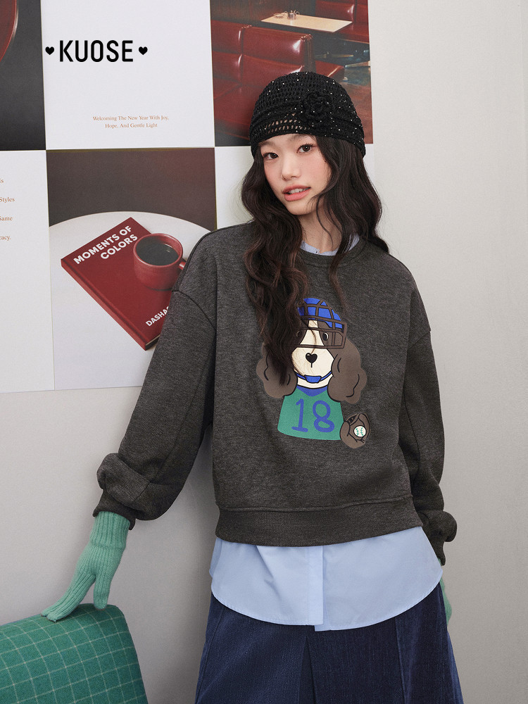Model wearing a dark gray graphic sweatshirt with a black beanie and mint gloves