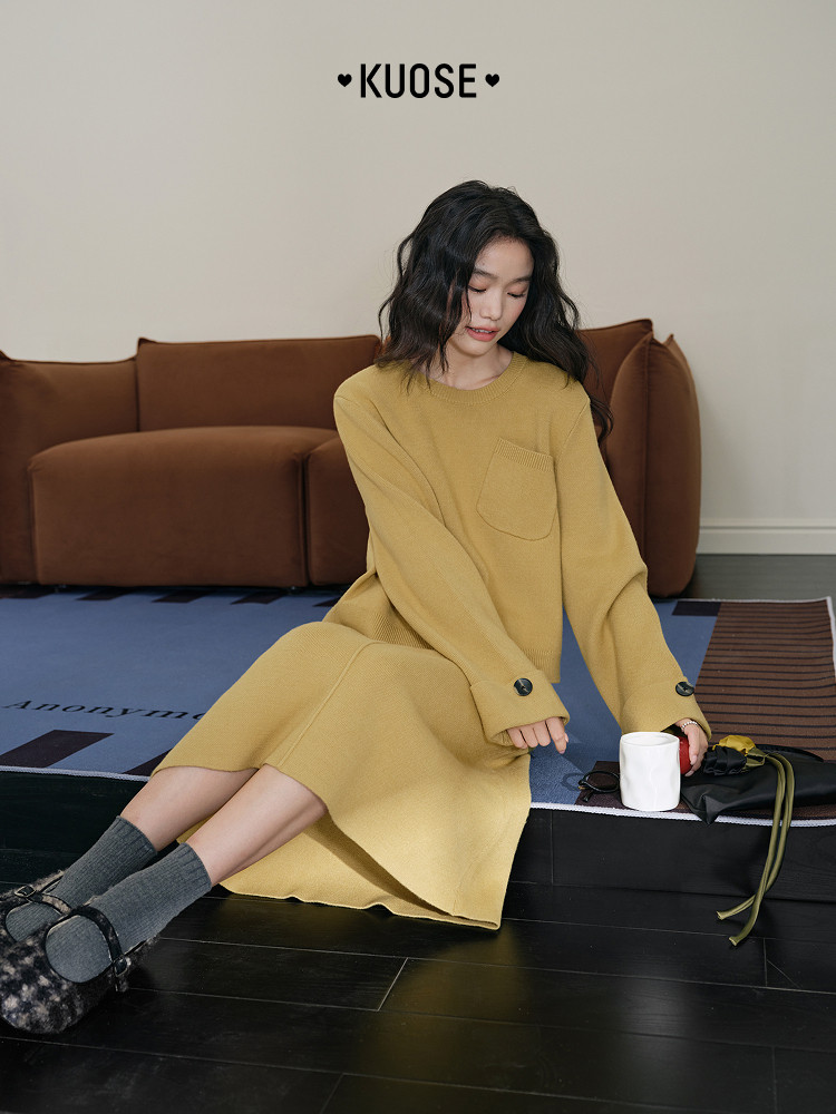 Model wearing a mustard yellow long-sleeve knit dress seated indoors