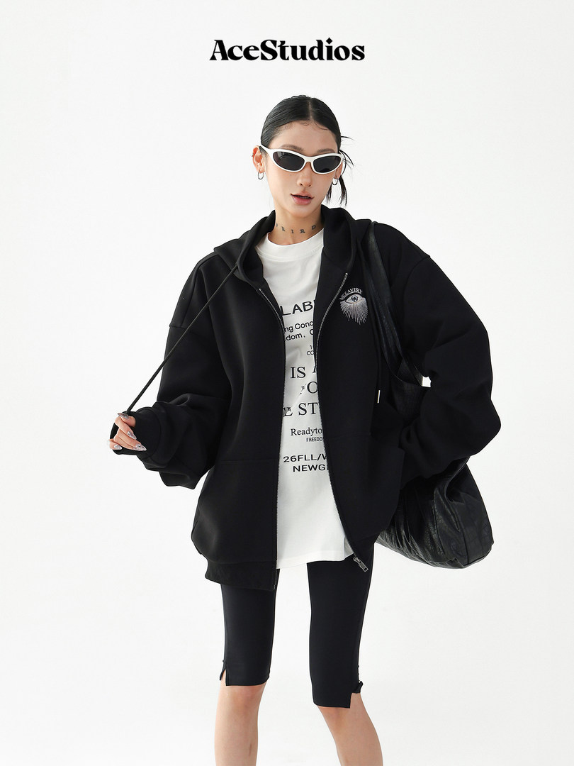 Fashion model wearing a black oversized hoodie over a white graphic tee with black shorts and sunglasses