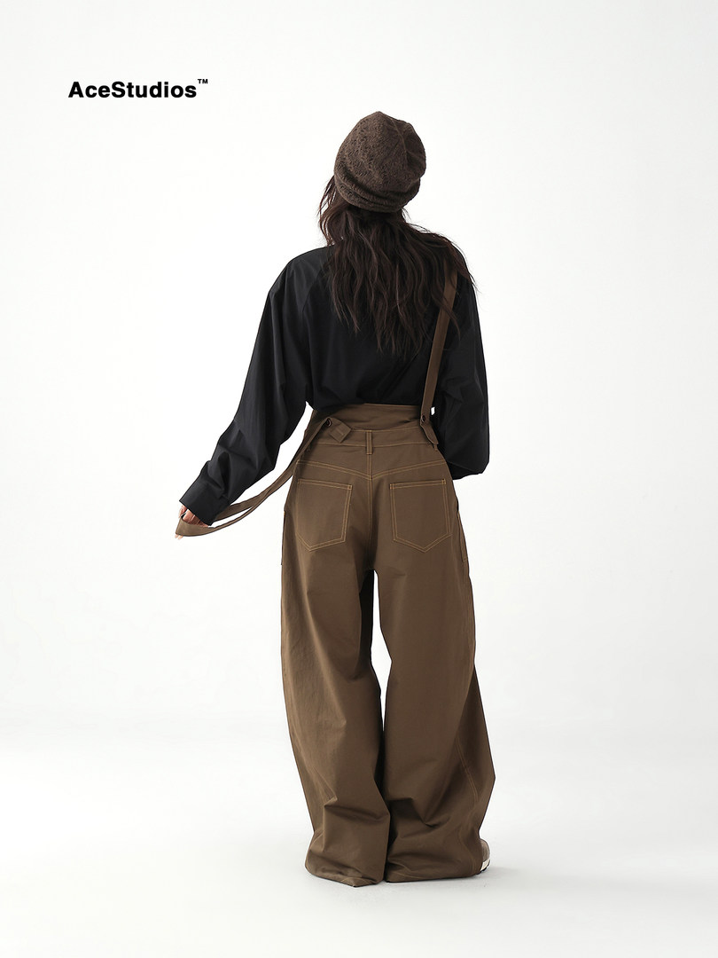 Model wearing black top with wide-leg brown pants and a beanie on a white background