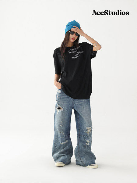 Model wearing a black graphic oversized T-shirt with baggy ripped blue jeans and a blue headwrap