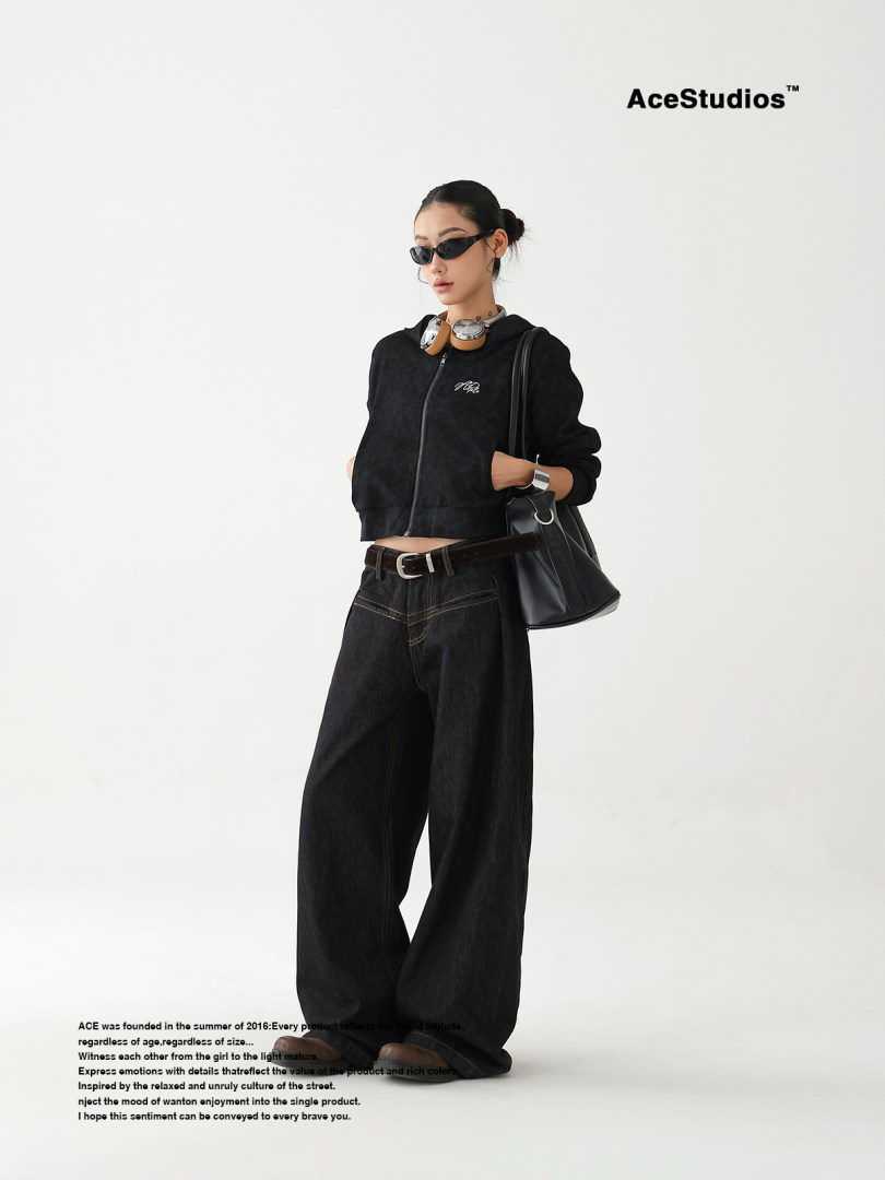 Model wearing a black cropped zip hoodie with wide-leg black jeans and a black handbag