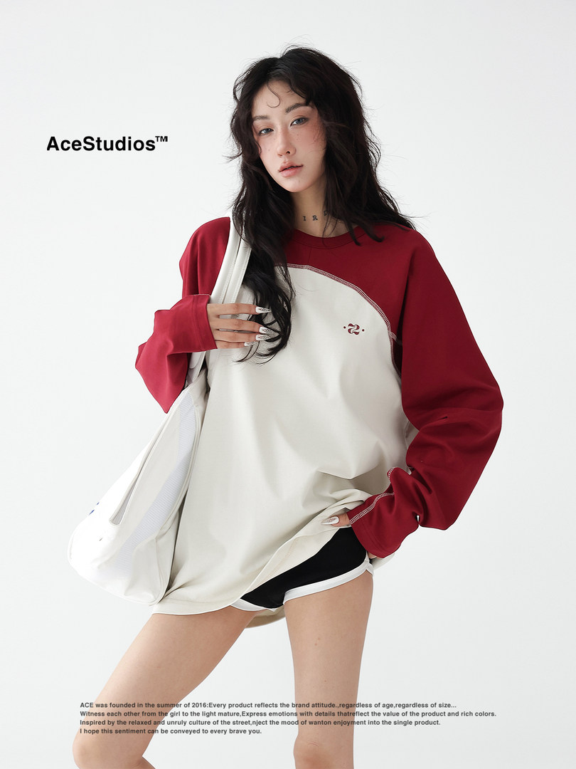Model wearing an oversized red-and-cream sweatshirt with shorts and a tote bag