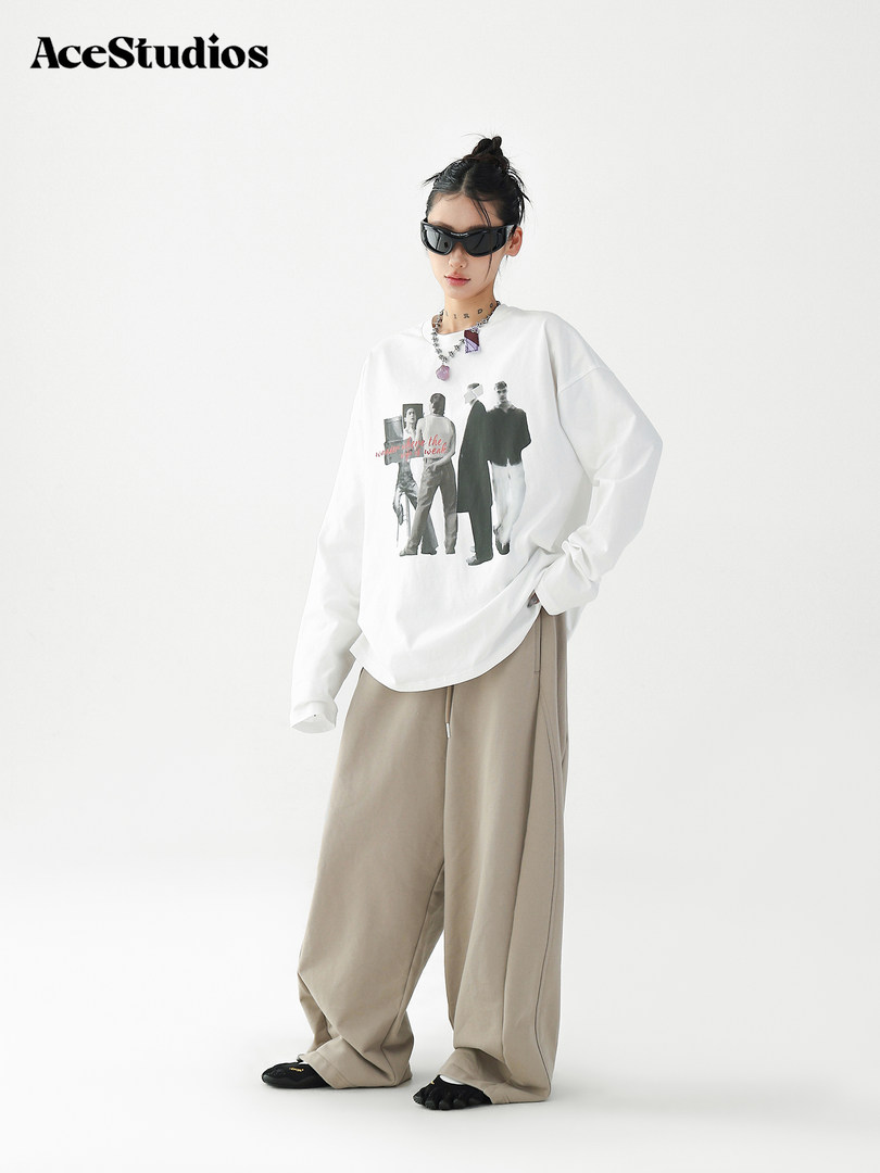 Model wearing a white graphic long-sleeve top with wide beige pants