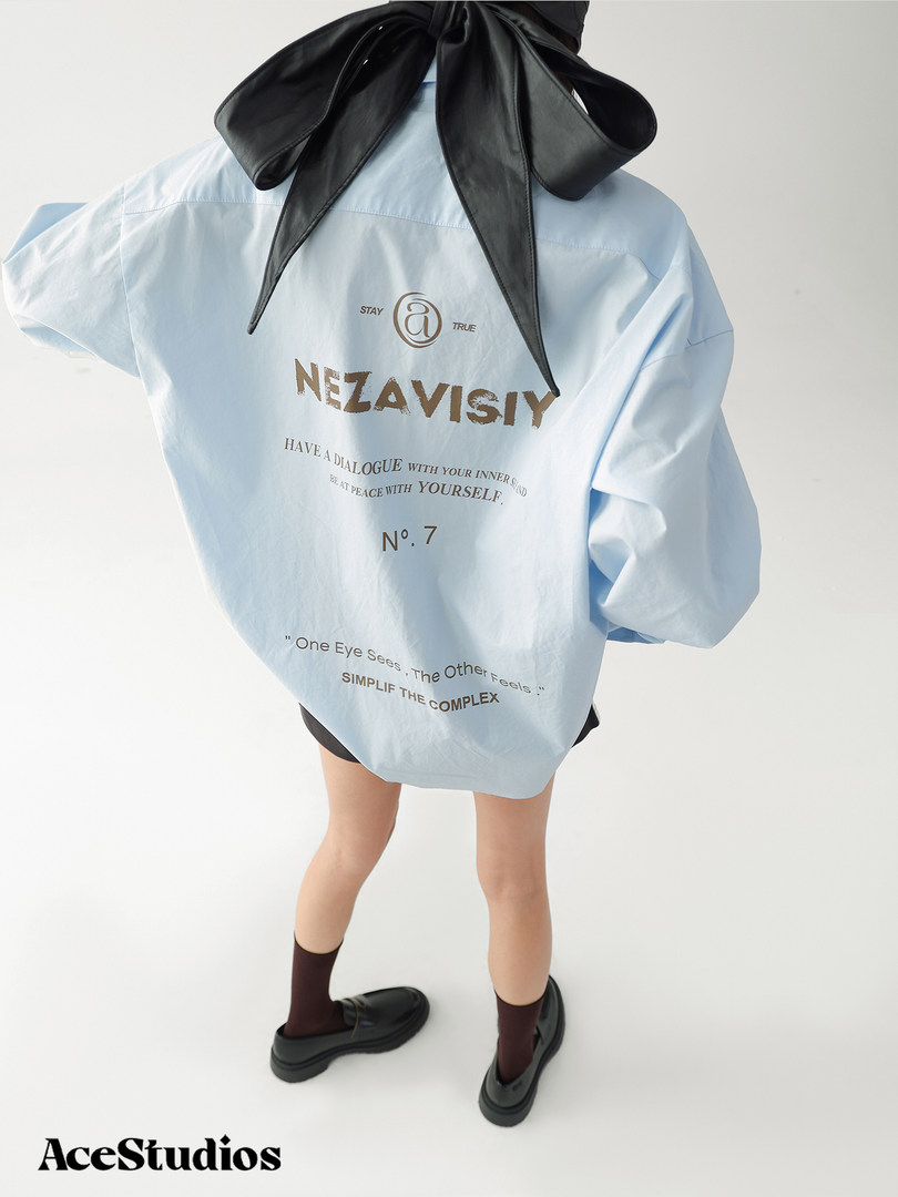 Model wearing an oversized light blue printed shirt with black bow detail