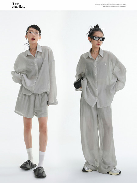 Model wearing a light gray loose-fit button-up shirt and matching wide-leg shorts/pants set