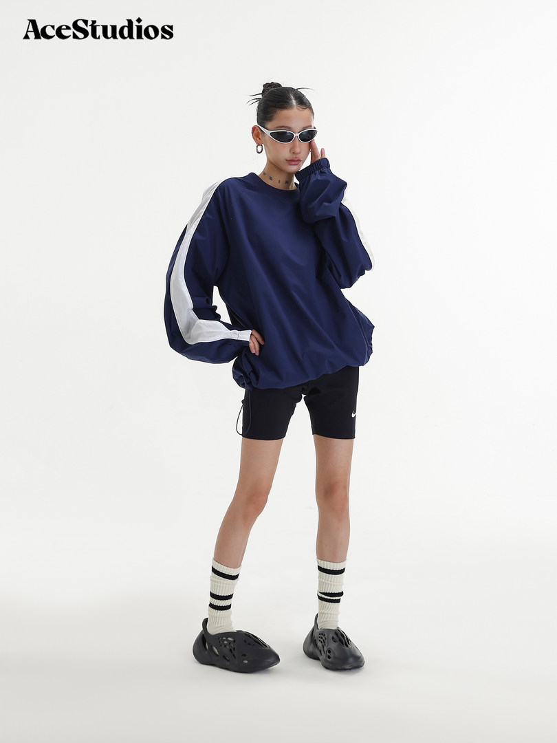 Model wearing an oversized navy long-sleeve top with white side stripes and black shorts
