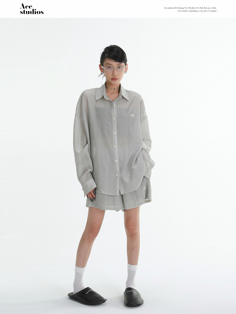 Model wearing a light gray oversized shirt and shorts set