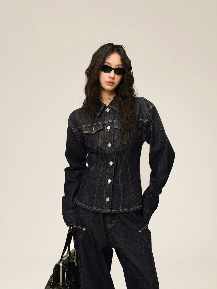 Model wearing a dark denim jacket and matching jeans with black sunglasses