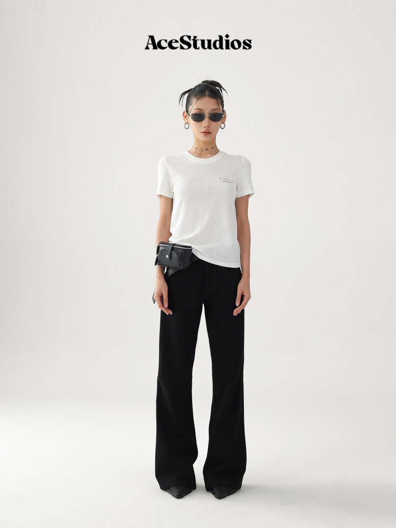 Model wearing a white short-sleeve T-shirt with black wide-leg pants and a black belt bag