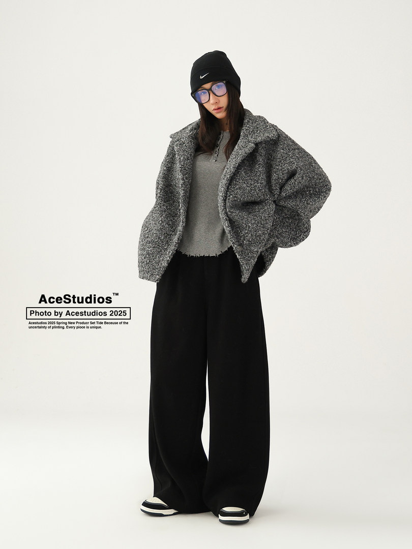 Model wearing a gray oversized textured jacket with black wide-leg pants and a black beanie