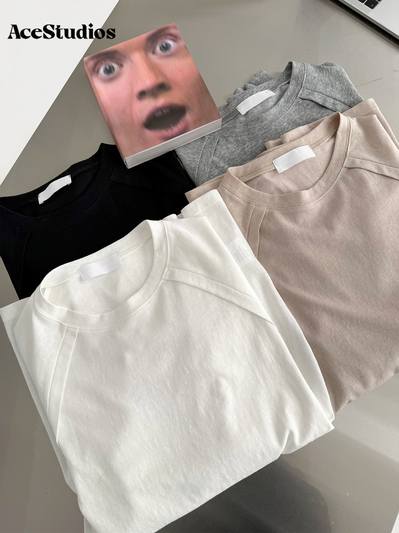 Folded plain crewneck t-shirts in black, white, gray, and beige