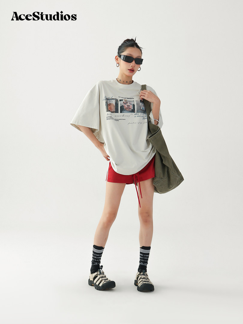 Model wearing an oversized graphic T-shirt with red shorts and sandals