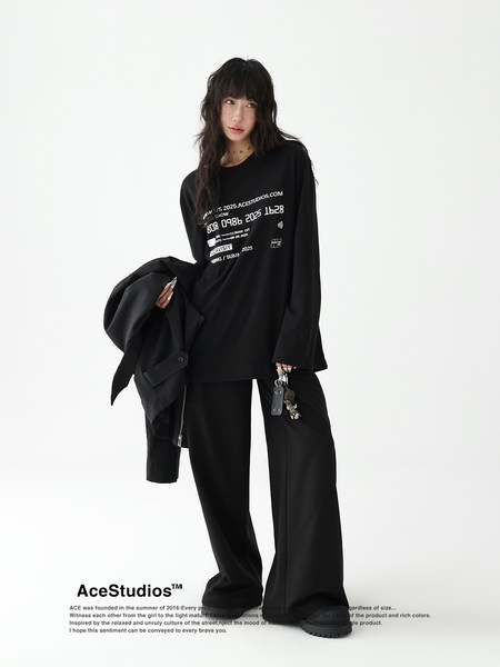 Model wearing a black streetwear outfit with printed long-sleeve top and wide-leg pants