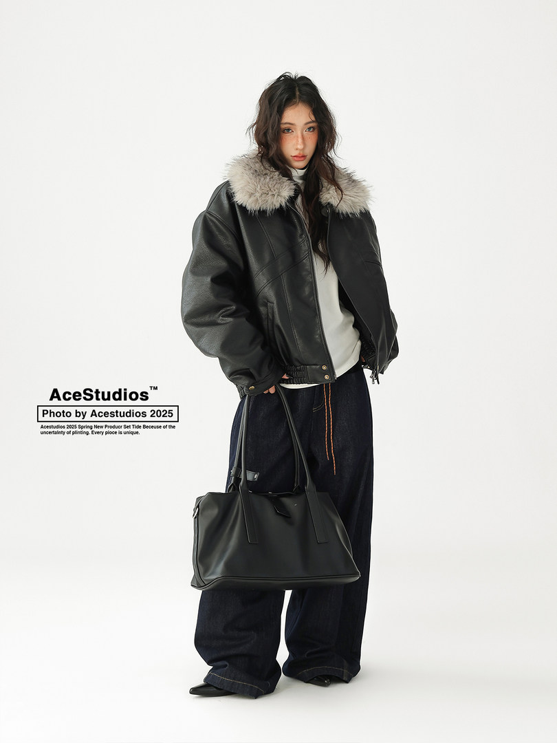 Model wearing a black leather jacket with faux fur collar and carrying a black tote bag