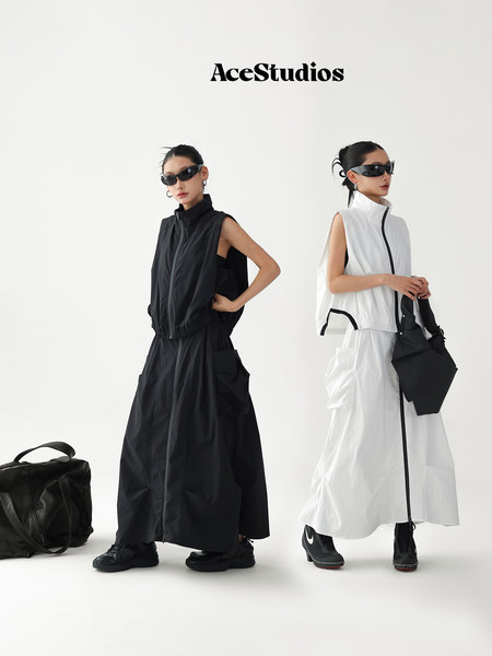 Models wearing black and white sleeveless zip-front long outfits with sunglasses
