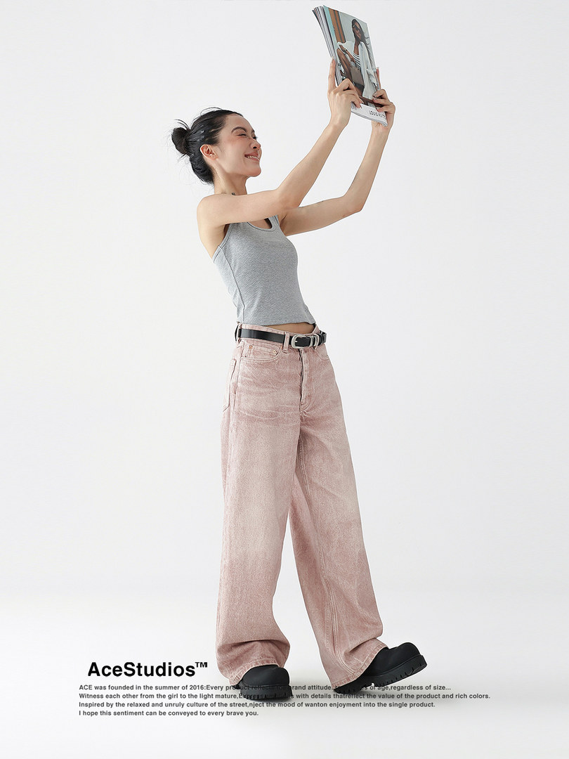 Model wearing a gray tank top with pink wide-leg pants and black shoes on a white background