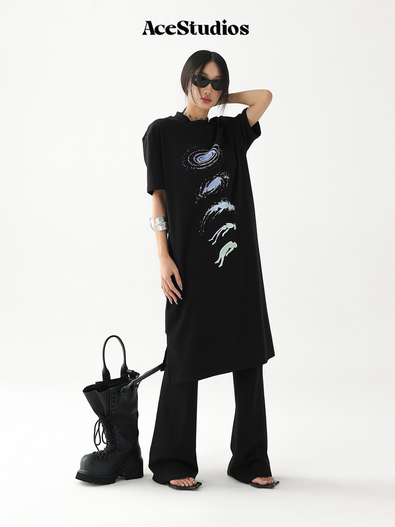 Model wearing a black oversized graphic T-shirt dress with wide-leg black pants and combat boots