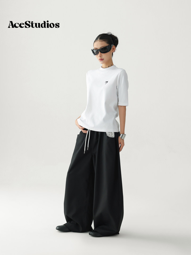 Model wearing a white top with black wide-leg pants and sunglasses
