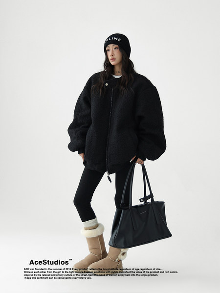 Fashion model wearing a black winter outfit with beanie, oversized coat, tote bag, and boots