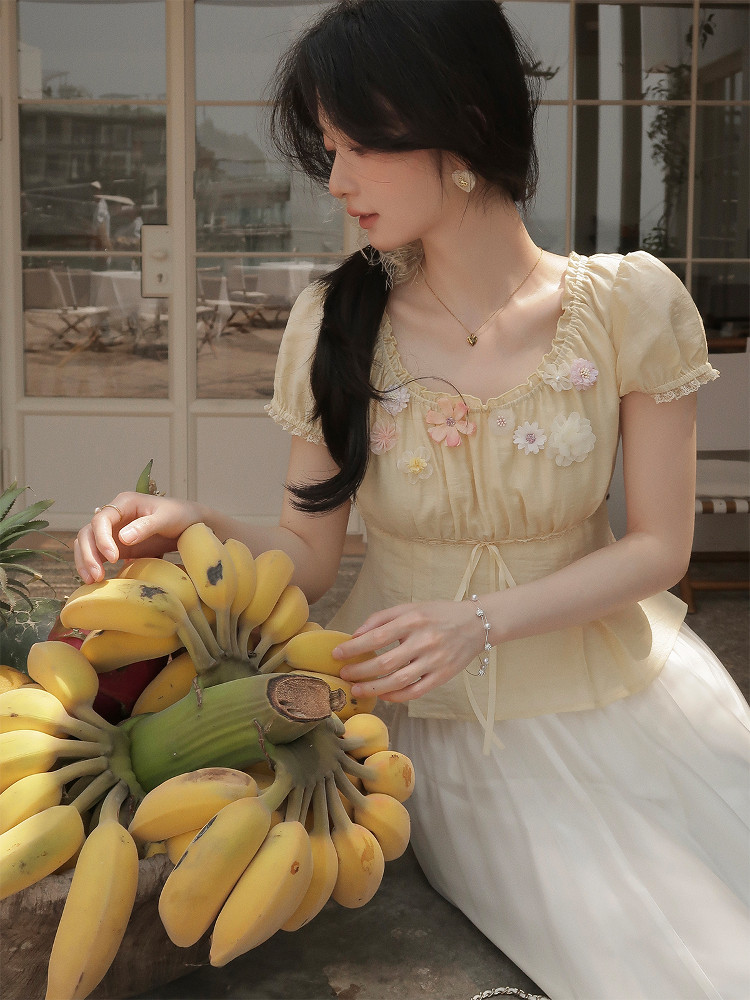 Woman wearing a pale yellow floral short-sleeve dress or top with a white skirt