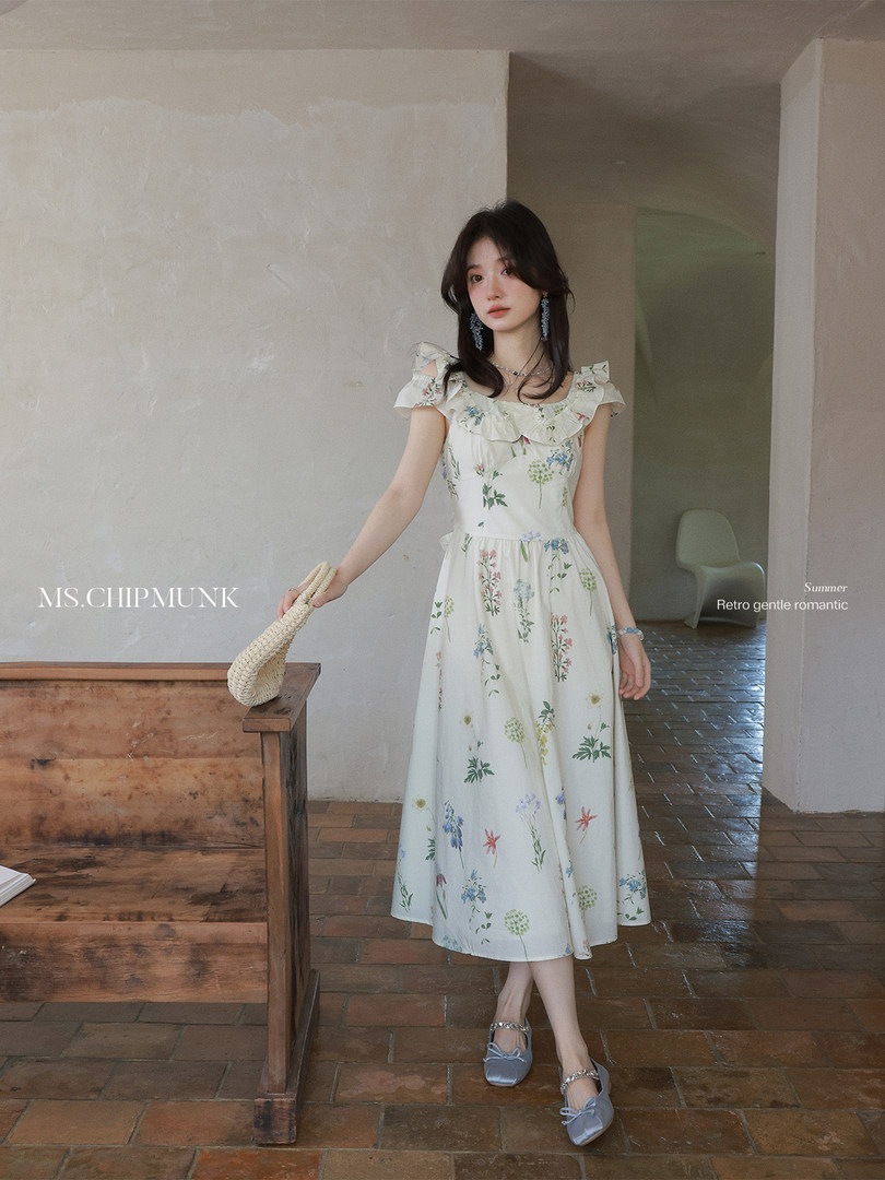 Model wearing a white floral midi dress with ruffled shoulders and mary jane flats