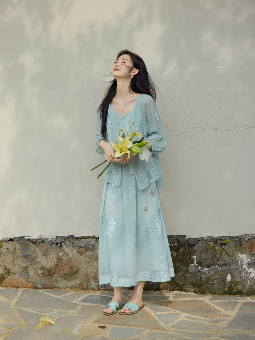 Model wearing a light blue embroidered dress set while holding flowers