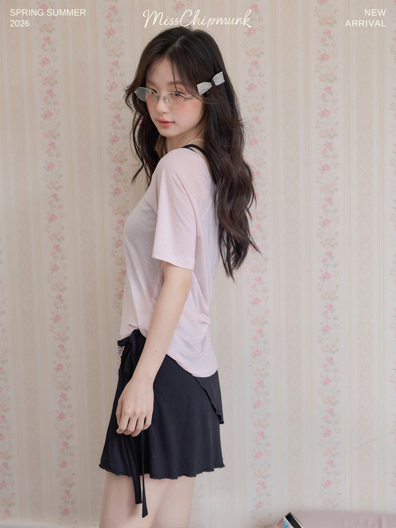 Model wearing a light pink short-sleeve top and black mini skirt