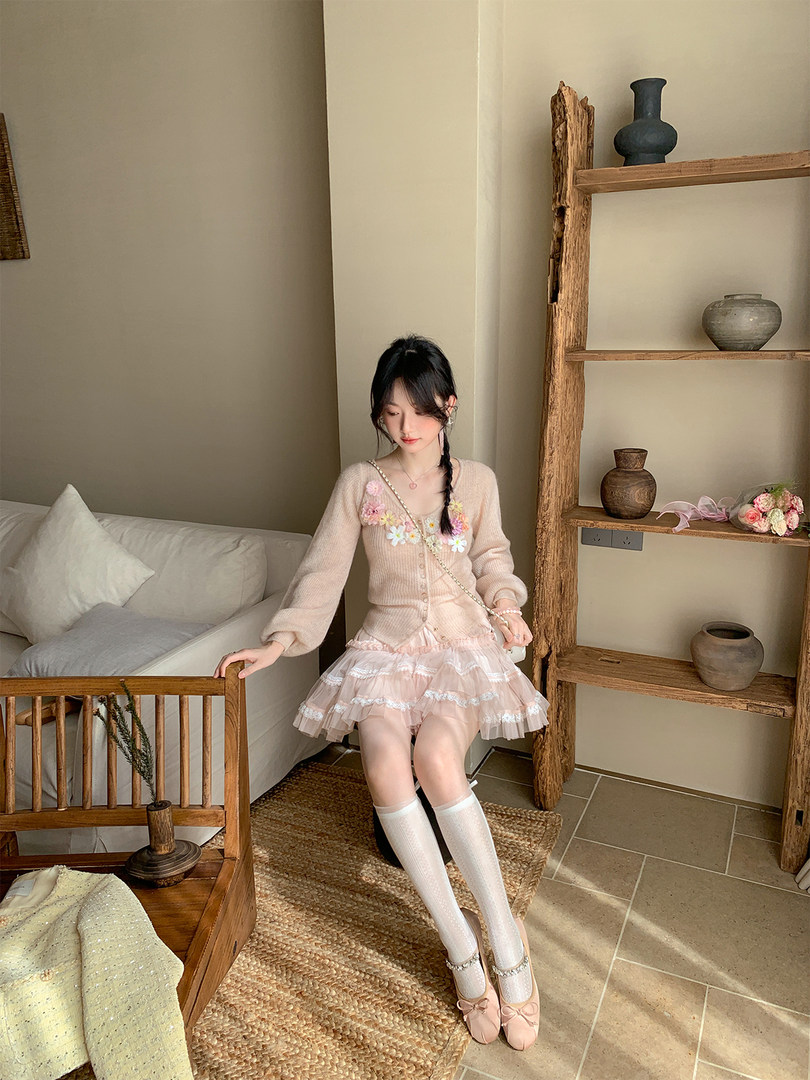 Woman wearing a pastel pink floral cardigan and ruffled skirt outfit