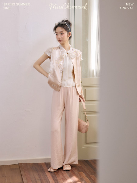 Model wearing a pastel pink sleeveless top with wide-leg pants and a small shoulder bag