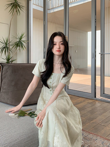 Woman wearing a light cream floral dress seated indoors