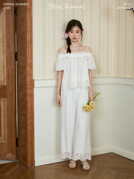 Young woman wearing a white off-shoulder lace-trim top and wide-leg pants