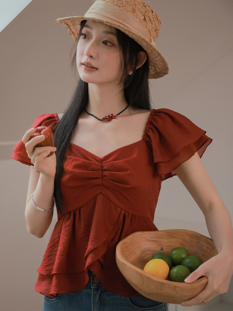 Woman wearing a red ruffled short-sleeve blouse with a straw hat