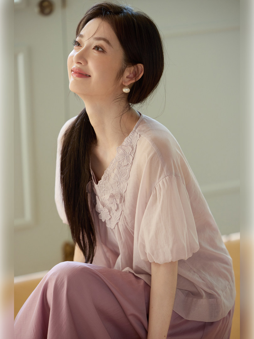 Woman wearing a light pink sheer embroidered blouse and matching pants