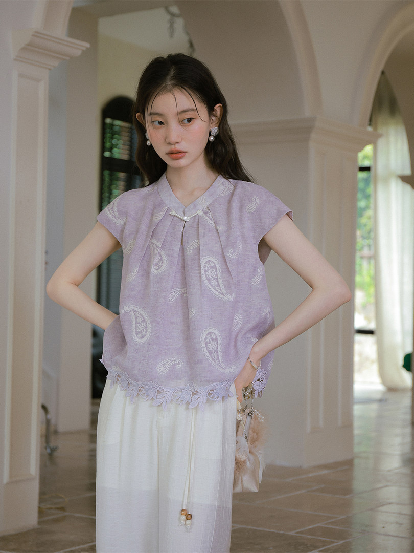 Model wearing a light lavender embroidered short-sleeve top with a white skirt