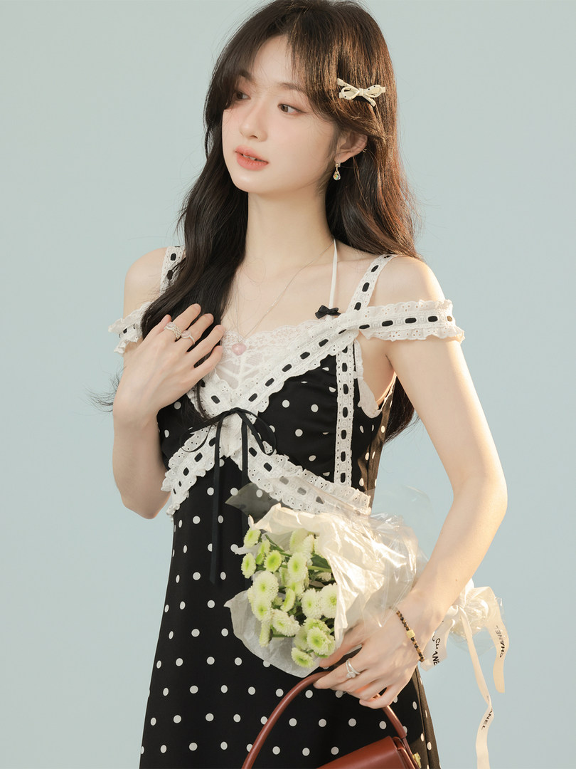 Black polka dot dress with white lace trim worn by a model