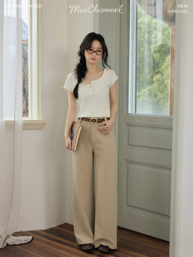 Model wearing a cream short-sleeve top with beige wide-leg pants