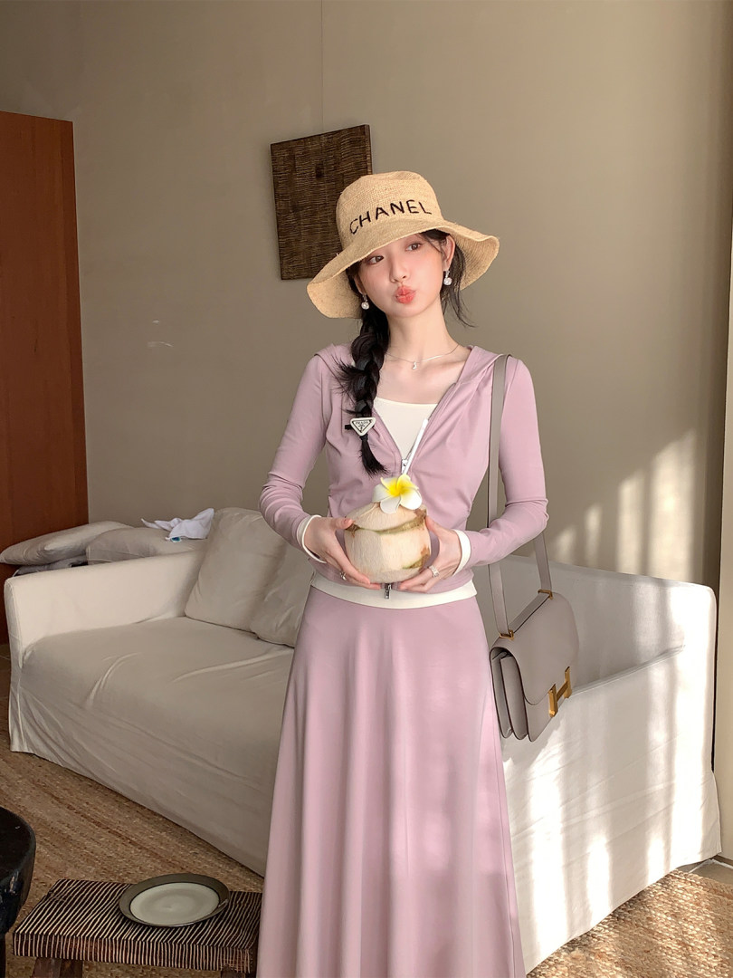 Woman wearing a pink long-sleeve matching skirt set with a straw hat and handbag
