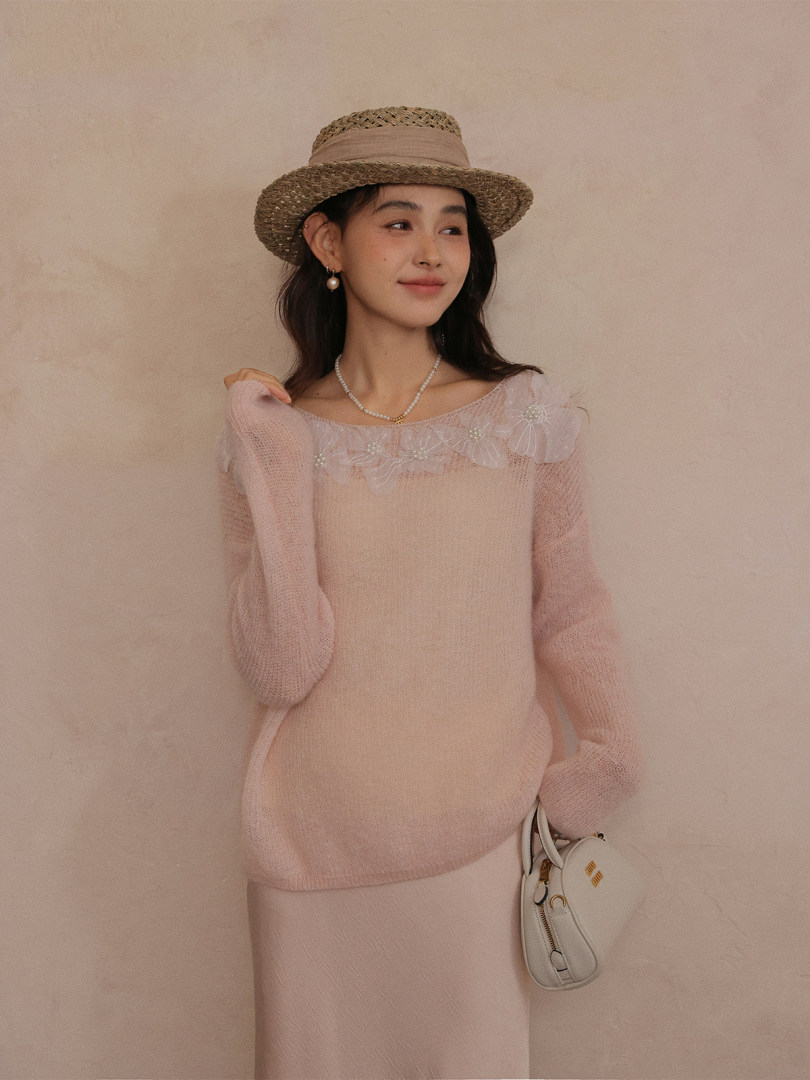 Model wearing a light pink sheer knit sweater with floral neckline details and a straw hat